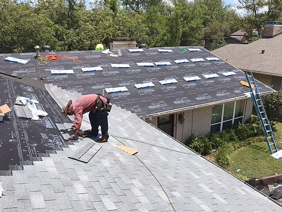 A roofer laying new shingles over fresh underlayment