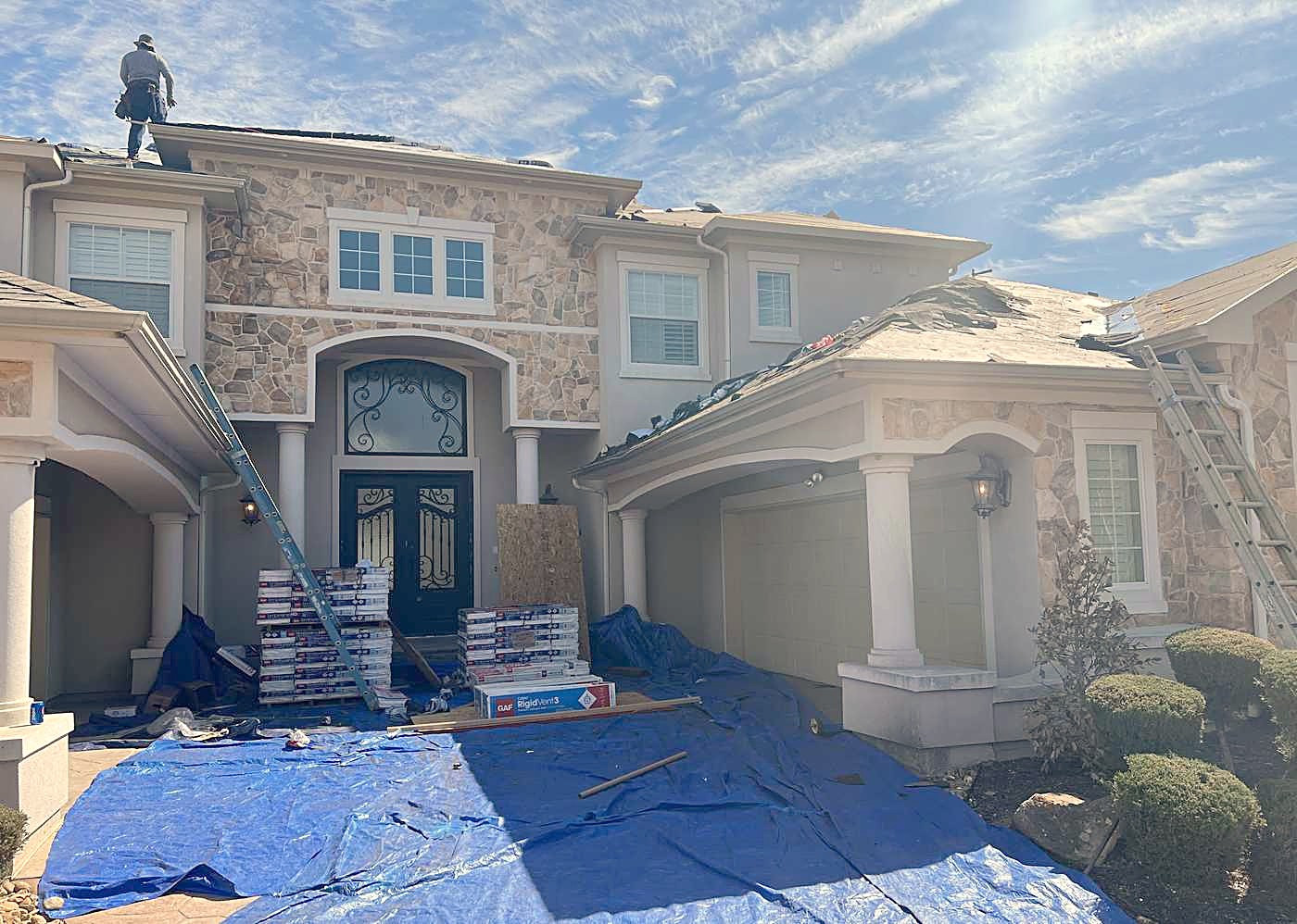 Tarps down around a house with somebody on the ridge