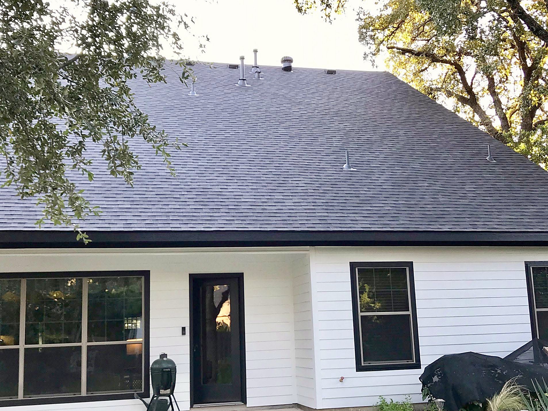 A white-sided home with a new dark shingle roof